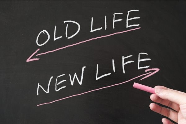 Hand drawing arrows with the words ‘Old Life’ and ‘New Life’ on a chalkboard